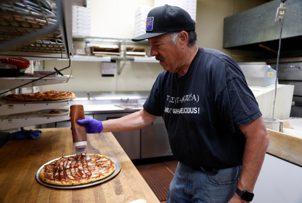 Al Vallorz, co-owner of Tony & Alba's Pizza and Pasta, adds a drizzle of Memphis barbecue sauce to the pizza, as the ChatGPT recipe called for. (Nhat V. Meyer/Bay Area News Group)